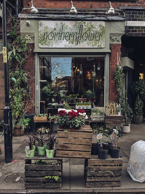 The storefront of Northenflower, a flower shop in South Norwood, featuring a white sign with green lettering and floral graphics. Outside, there are wooden crates holding potted plants and fresh flowe